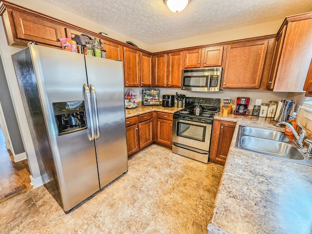 kitchen featuring light stone countertops, appliances with stainless steel finishes, sink, and a textured ceiling