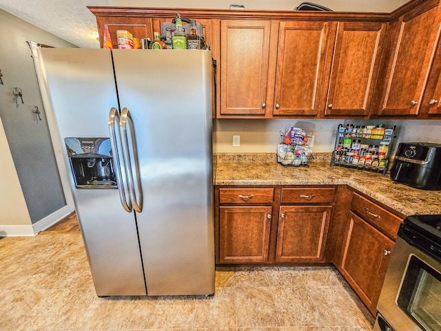 kitchen featuring appliances with stainless steel finishes, a textured ceiling, and light stone counters