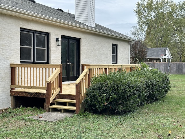 view of exterior entry with a lawn and a deck