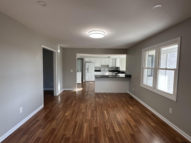 kitchen with white cabinetry, dark hardwood / wood-style flooring, white refrigerator with ice dispenser, and kitchen peninsula