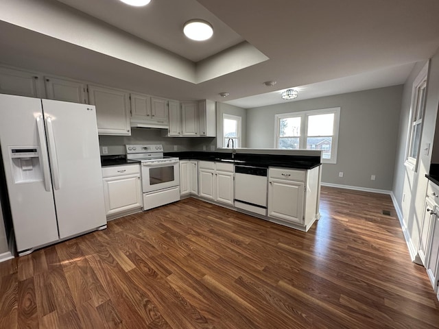 kitchen with white appliances, dark hardwood / wood-style floors, kitchen peninsula, and white cabinets