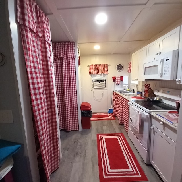 kitchen featuring white appliances, white cabinets, sink, light wood-type flooring, and a wall unit AC