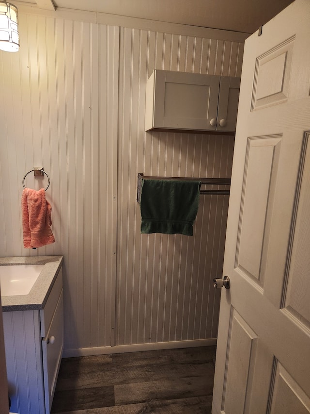 bathroom with wooden walls, vanity, and wood-type flooring