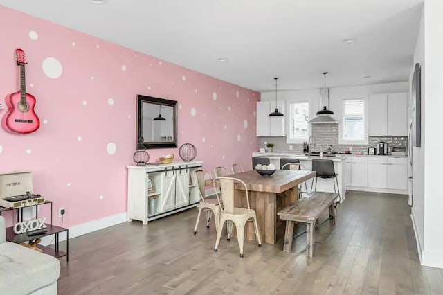 kitchen featuring backsplash, decorative light fixtures, an island with sink, white cabinets, and dark wood-type flooring