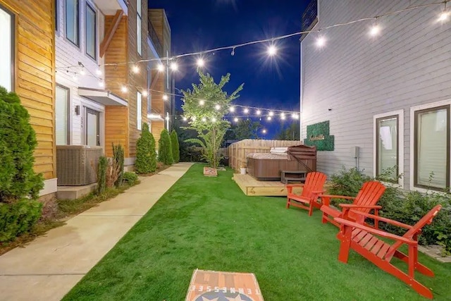 yard at twilight with central AC unit and a hot tub