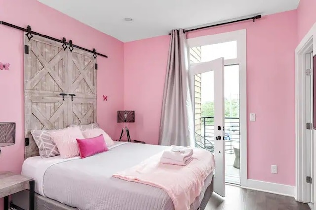 bedroom with a barn door, hardwood / wood-style floors, and access to exterior