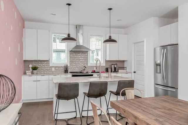 kitchen with white cabinets, hanging light fixtures, wall chimney exhaust hood, and appliances with stainless steel finishes