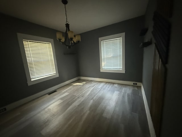 unfurnished dining area featuring wood-type flooring and a notable chandelier