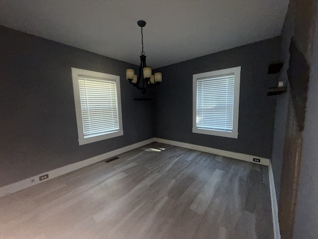 unfurnished dining area with hardwood / wood-style floors and an inviting chandelier