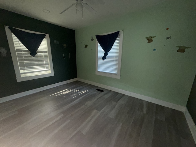 empty room featuring a healthy amount of sunlight, hardwood / wood-style flooring, and ceiling fan