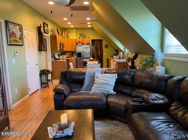 living room featuring light hardwood / wood-style flooring, ceiling fan, and sink