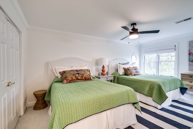 carpeted bedroom with a closet, ceiling fan, and crown molding