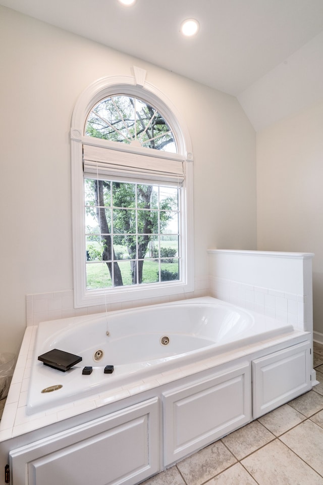 bathroom with tile patterned flooring, a bathtub, and lofted ceiling