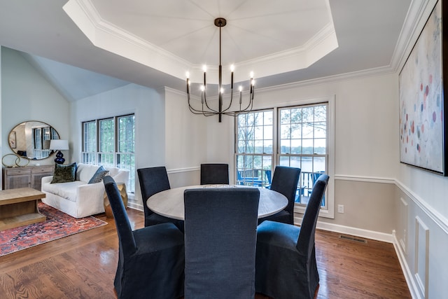 dining space featuring dark wood-type flooring, a tray ceiling, and a wealth of natural light