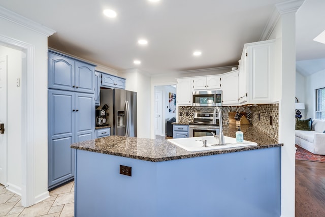 kitchen with sink, kitchen peninsula, appliances with stainless steel finishes, blue cabinets, and white cabinets