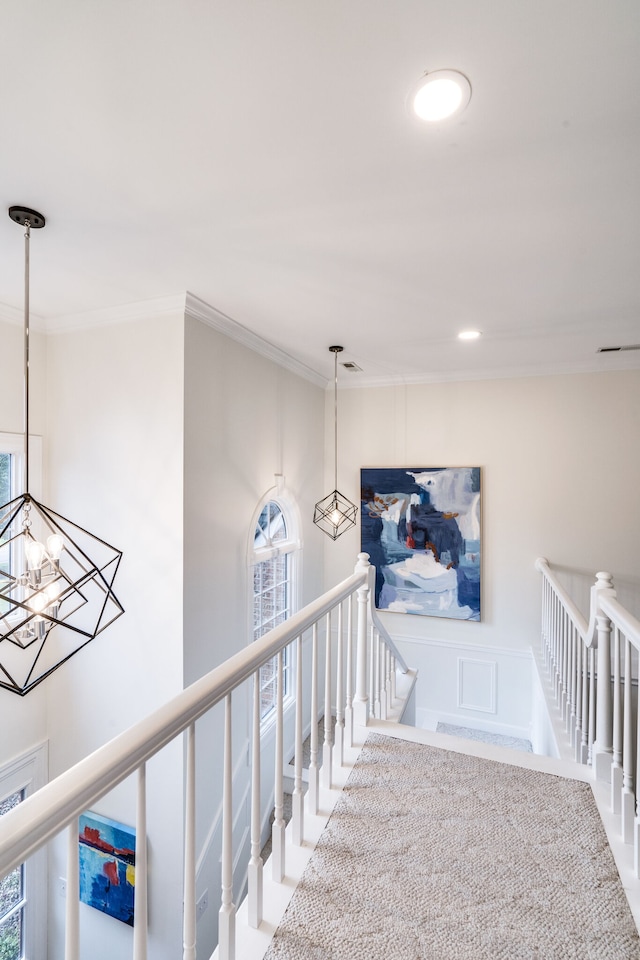 staircase featuring carpet flooring, a notable chandelier, and ornamental molding