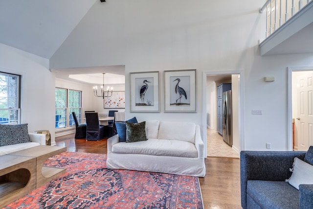 living room with wood-type flooring, a chandelier, and high vaulted ceiling