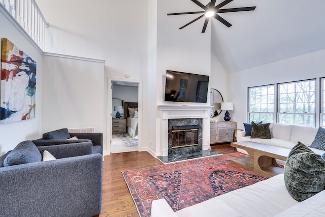 living room with high vaulted ceiling, hardwood / wood-style floors, ceiling fan, and a high end fireplace