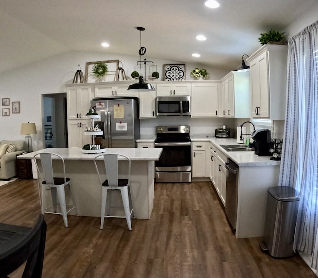 kitchen featuring lofted ceiling, sink, white cabinetry, appliances with stainless steel finishes, and decorative light fixtures