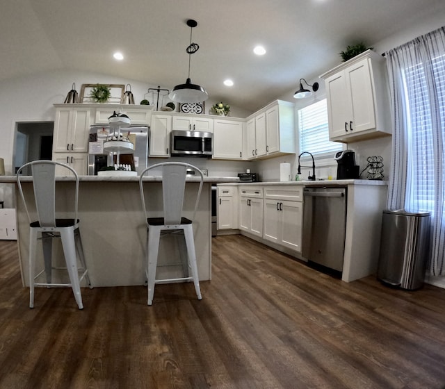 kitchen with white cabinets, stainless steel appliances, decorative light fixtures, and vaulted ceiling