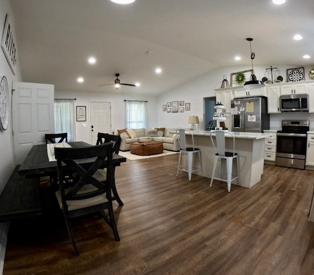 kitchen with a kitchen bar, vaulted ceiling, pendant lighting, appliances with stainless steel finishes, and white cabinetry