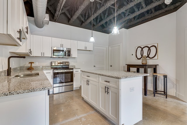 kitchen featuring stainless steel appliances, a kitchen island, white cabinetry, pendant lighting, and sink