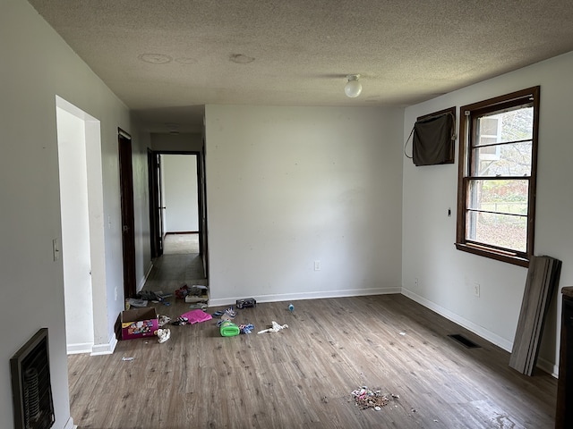 unfurnished room featuring light wood-type flooring and a textured ceiling