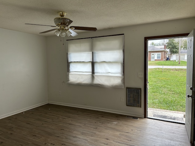 unfurnished room featuring dark hardwood / wood-style flooring, heating unit, a textured ceiling, and ceiling fan