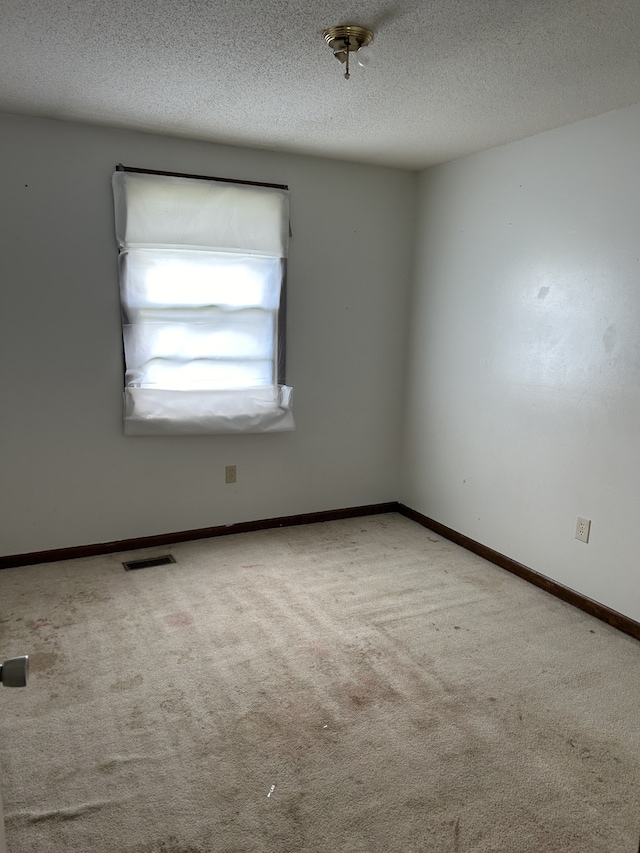 carpeted empty room with a textured ceiling