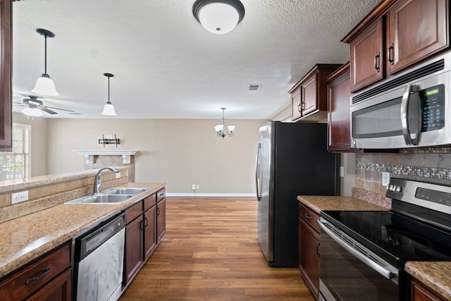 kitchen with pendant lighting, light hardwood / wood-style floors, sink, and appliances with stainless steel finishes