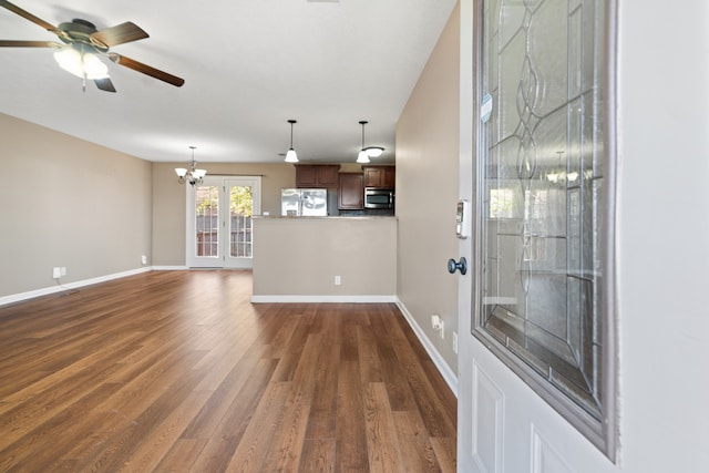 unfurnished living room with ceiling fan with notable chandelier, dark wood-type flooring, and french doors