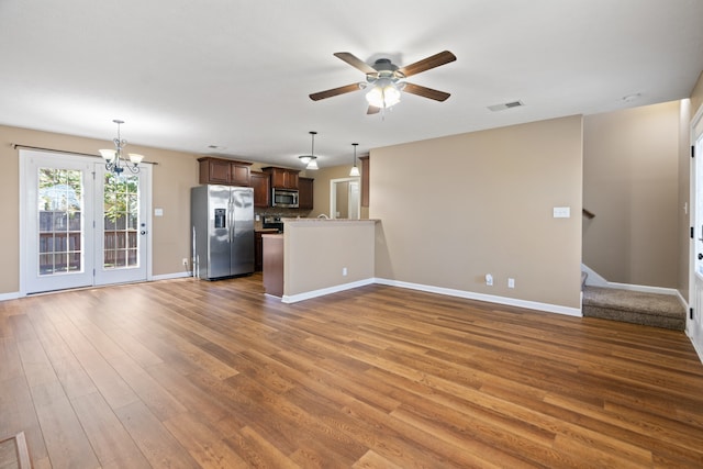 unfurnished living room with hardwood / wood-style floors and ceiling fan with notable chandelier