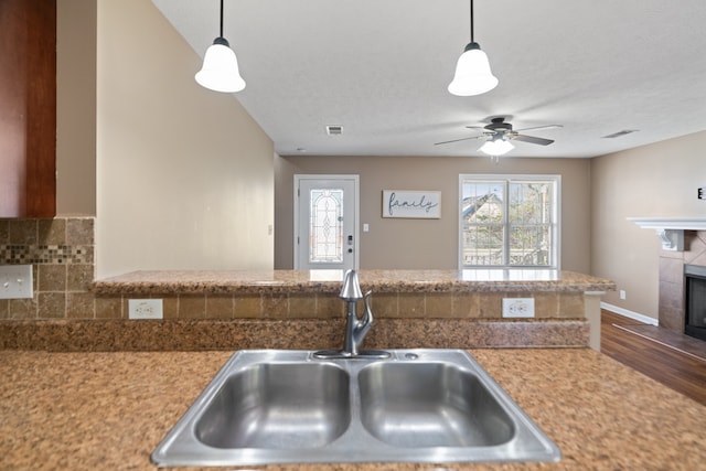 kitchen with a fireplace, wood-type flooring, decorative light fixtures, and sink