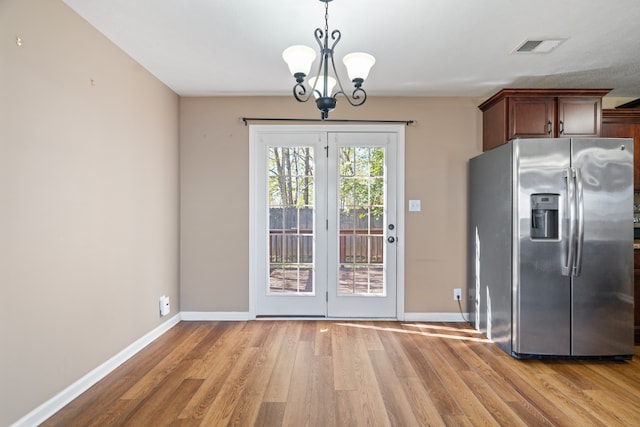 doorway featuring a chandelier and light hardwood / wood-style floors