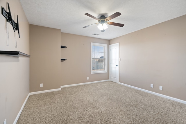 carpeted empty room with ceiling fan and a textured ceiling