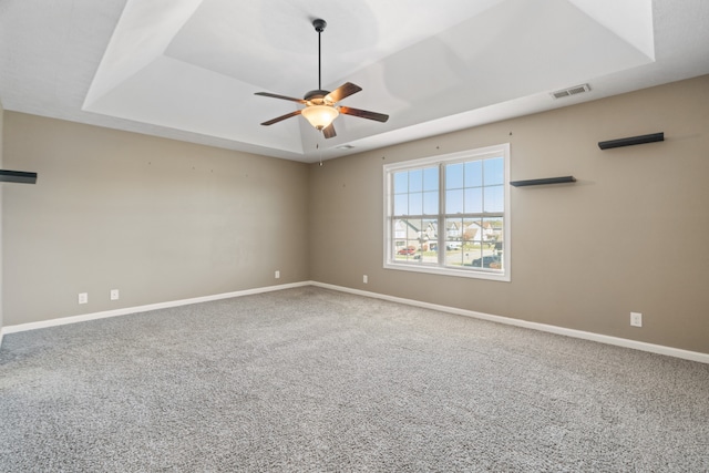 spare room featuring a tray ceiling, ceiling fan, and carpet flooring