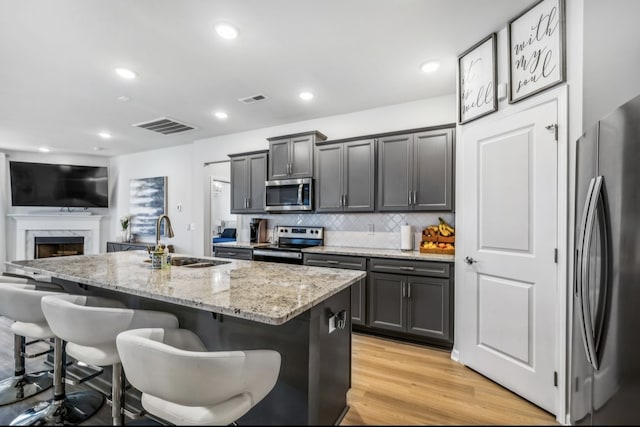 kitchen featuring a kitchen island with sink, a kitchen bar, stainless steel appliances, and sink