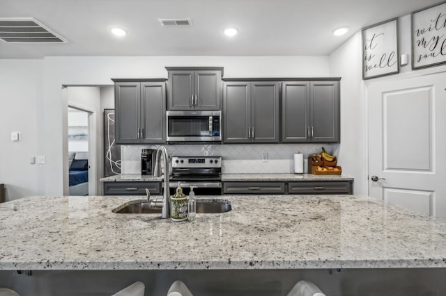 kitchen with a kitchen breakfast bar, stainless steel appliances, decorative backsplash, and sink