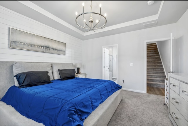 carpeted bedroom with ensuite bathroom and a tray ceiling