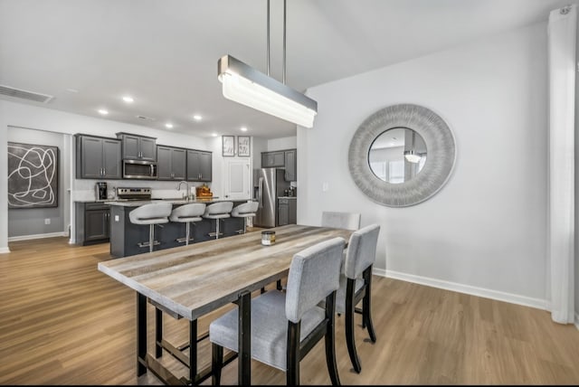 dining room with sink and light hardwood / wood-style flooring