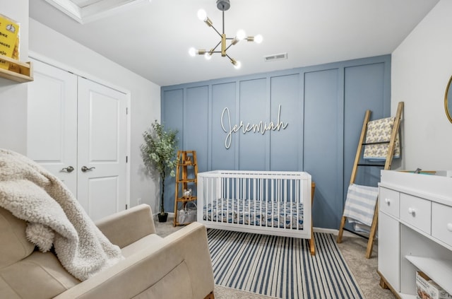 carpeted bedroom with a closet, an inviting chandelier, and a nursery area