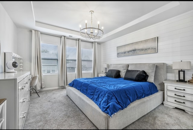 carpeted bedroom with a notable chandelier, wooden walls, and a tray ceiling