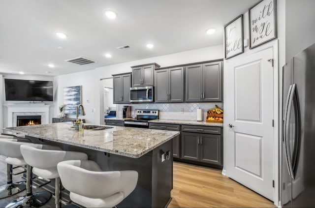 kitchen featuring an island with sink, sink, a kitchen bar, and stainless steel appliances