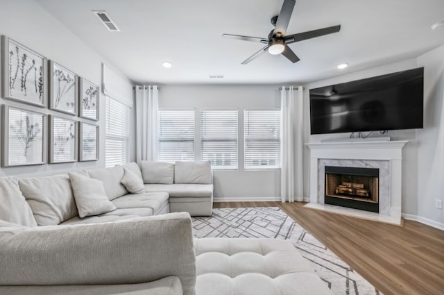 living room featuring hardwood / wood-style flooring, ceiling fan, and a high end fireplace