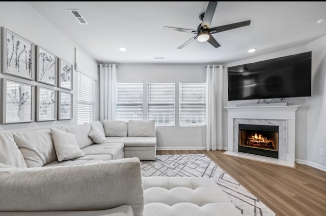 living room featuring hardwood / wood-style floors, ceiling fan, and a high end fireplace