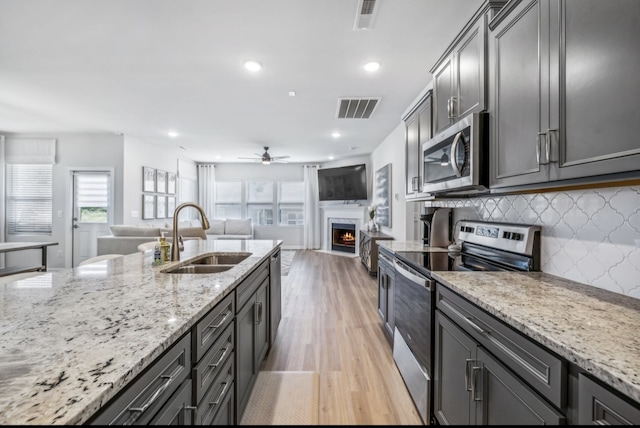 kitchen featuring plenty of natural light, sink, light stone counters, and appliances with stainless steel finishes