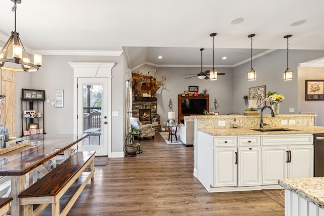 kitchen with a stone fireplace, sink, decorative light fixtures, and white cabinets