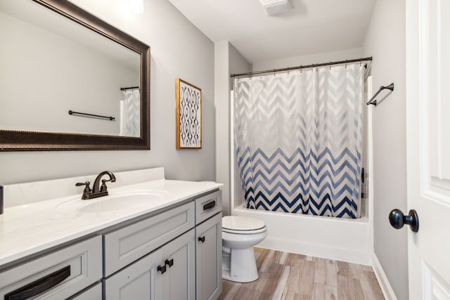 full bathroom with wood-type flooring, shower / bath combination with curtain, toilet, and vanity