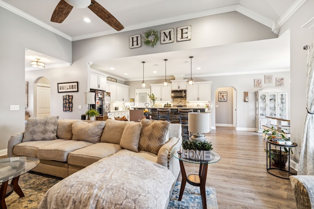 living room with ornamental molding, light wood-type flooring, and ceiling fan