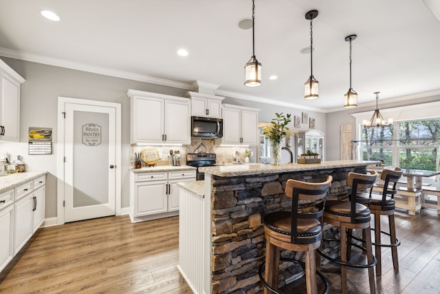 kitchen with white cabinets, stainless steel appliances, light stone counters, and light hardwood / wood-style flooring